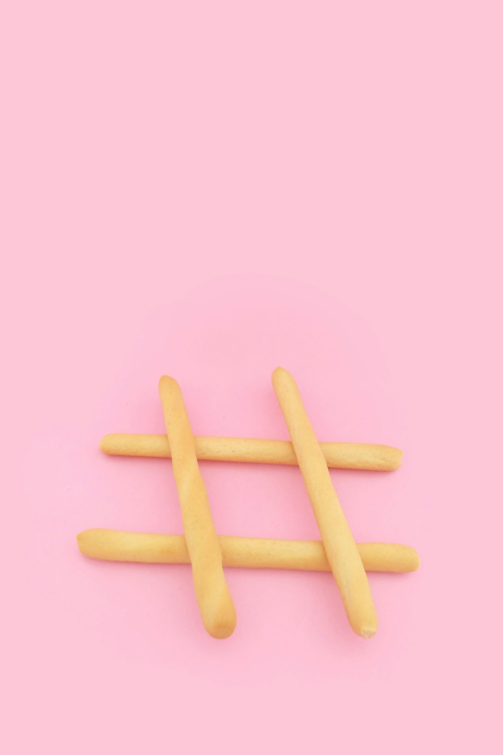 Four brown wooden sticks on pink surface