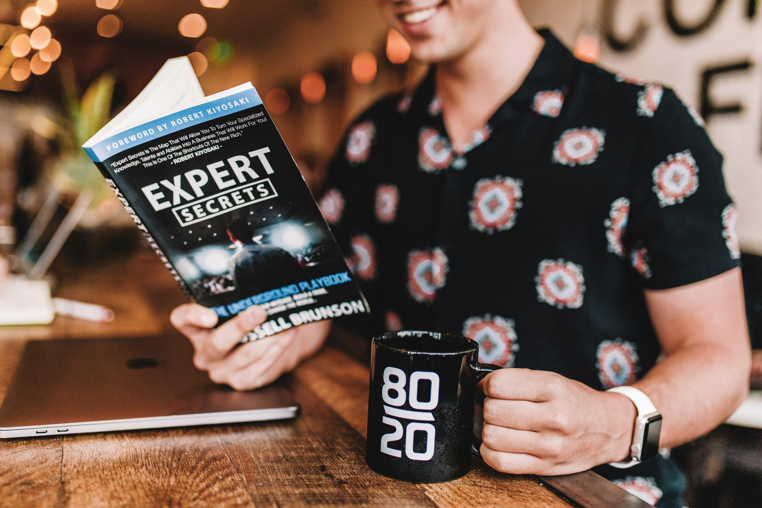 Smiling man reading book while holding mug