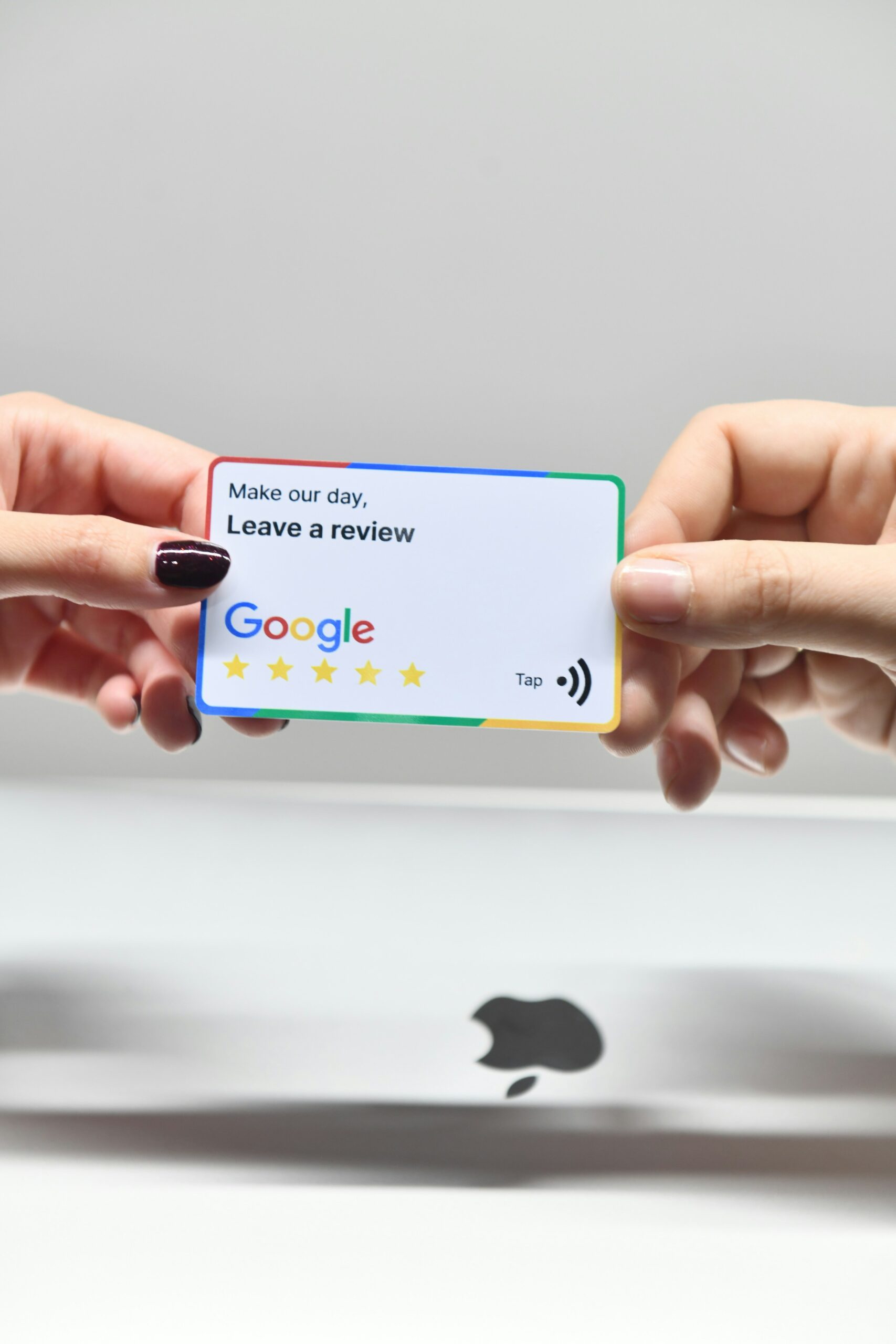 Two hands holding a google credit card in front of an apple logo